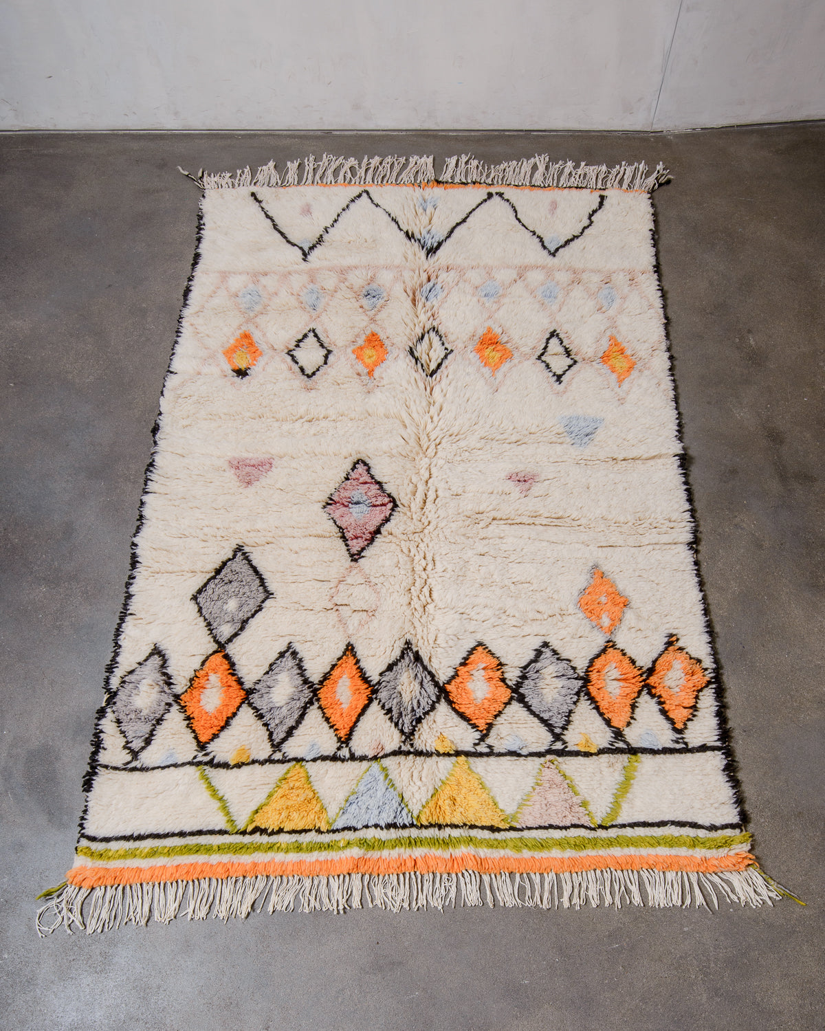 Berberlin Finest Rug in plush cream wool with a design made up of zigzags and diamonds laying flat of concrete studio floor.
